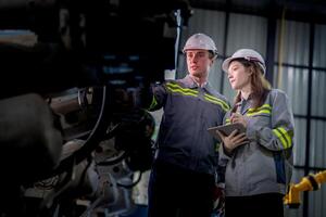Factory engineer woman inspecting on machine with smart tablet. Worker works at machine robot arm. The welding machine with a remote system in an industrial factory. Artificial intelligence concept. photo