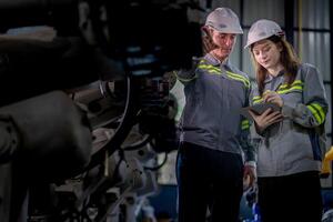 fábrica ingeniero mujer inspeccionando en máquina con inteligente tableta. trabajador trabajos a máquina robot brazo. el soldadura máquina con un remoto sistema en un industrial fábrica. artificial inteligencia concepto. foto