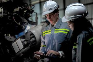 engineers check control heavy machine robot arm. Diverse Team of Industrial Robotics Engineers Gathered Around Machine. Professional Machinery Operators repair electric robot on bright digital panel. photo