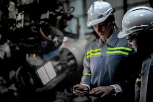 Factory engineer woman inspecting on machine with smart tablet. Worker works at machine robot arm. The welding machine with a remote system in an industrial factory. Artificial intelligence concept. photo