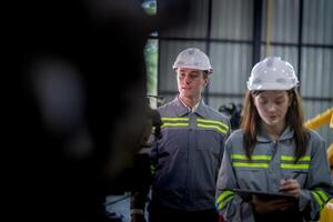 Factory engineer woman inspecting on machine with smart tablet. Worker works at machine robot arm. The welding machine with a remote system in an industrial factory. Artificial intelligence concept. photo