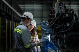 Factory engineer woman inspecting on machine with smart tablet. Worker works at machine robot arm. The welding machine with a remote system in an industrial factory. Artificial intelligence concept. photo