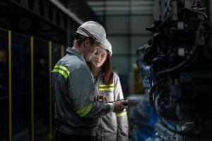 Factory engineer woman inspecting on machine with smart tablet. Worker works at machine robot arm. The welding machine with a remote system in an industrial factory. Artificial intelligence concept. photo