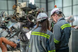 Factory engineer woman inspecting on machine with smart tablet. Worker works at machine robot arm. The welding machine with a remote system in an industrial factory. Artificial intelligence concept. photo