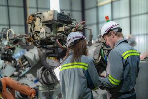 Factory engineer woman inspecting on machine with smart tablet. Worker works at machine robot arm. The welding machine with a remote system in an industrial factory. Artificial intelligence concept. photo