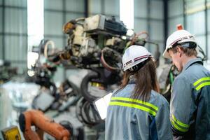 engineers check control heavy machine robot arm. Diverse Team of Industrial Robotics Engineers Gathered Around Machine. Professional Machinery Operators repair electric robot on bright digital panel. photo