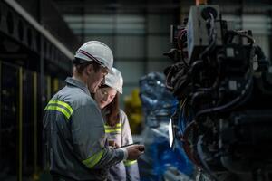 Factory engineer woman inspecting on machine with smart tablet. Worker works at machine robot arm. The welding machine with a remote system in an industrial factory. Artificial intelligence concept. photo