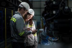 Factory engineer woman inspecting on machine with smart tablet. Worker works at machine robot arm. The welding machine with a remote system in an industrial factory. Artificial intelligence concept. photo