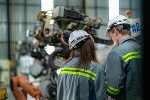 engineers check control heavy machine robot arm. Diverse Team of Industrial Robotics Engineers Gathered Around Machine. Professional Machinery Operators repair electric robot on bright digital panel. photo