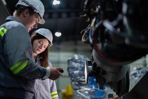 engineers check control heavy machine robot arm. Diverse Team of Industrial Robotics Engineers Gathered Around Machine. Professional Machinery Operators repair electric robot on bright digital panel. photo