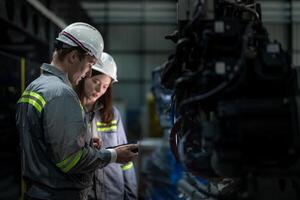Factory engineer woman inspecting on machine with smart tablet. Worker works at machine robot arm. The welding machine with a remote system in an industrial factory. Artificial intelligence concept. photo