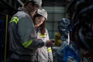 engineers check control heavy machine robot arm. Diverse Team of Industrial Robotics Engineers Gathered Around Machine. Professional Machinery Operators repair electric robot on bright digital panel. photo