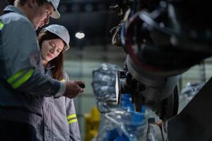 engineers check control heavy machine robot arm. Diverse Team of Industrial Robotics Engineers Gathered Around Machine. Professional Machinery Operators repair electric robot on bright digital panel. photo