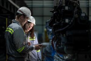 Factory engineer woman inspecting on machine with smart tablet. Worker works at machine robot arm. The welding machine with a remote system in an industrial factory. Artificial intelligence concept. photo