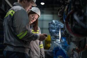 engineers check control heavy machine robot arm. Diverse Team of Industrial Robotics Engineers Gathered Around Machine. Professional Machinery Operators repair electric robot on bright digital panel. photo