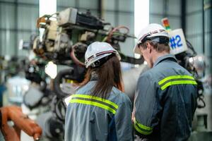 engineers check control heavy machine robot arm. Diverse Team of Industrial Robotics Engineers Gathered Around Machine. Professional Machinery Operators repair electric robot on bright digital panel. photo