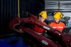 group of male engineer workers maintenance automatic robotic arm machine in a dark room factory. worker checking and repairing automatic robot hand machine. Worker wearing safety glasses and helmet. photo