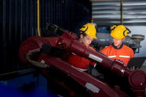 group of male engineer workers maintenance automatic robotic arm machine in a dark room factory. worker checking and repairing automatic robot hand machine. Worker wearing safety glasses and helmet. photo