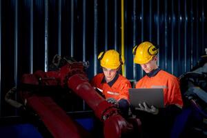 group of male engineer workers maintenance automatic robotic arm machine in a dark room factory. worker checking and repairing automatic robot hand machine. Worker wearing safety glasses and helmet. photo