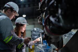 fábrica ingeniero mujer inspeccionando en máquina con inteligente tableta. trabajador trabajos a máquina robot brazo. el soldadura máquina con un remoto sistema en un industrial fábrica. artificial inteligencia concepto. foto