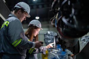 engineers check control heavy machine robot arm. Diverse Team of Industrial Robotics Engineers Gathered Around Machine. Professional Machinery Operators repair electric robot on bright digital panel. photo