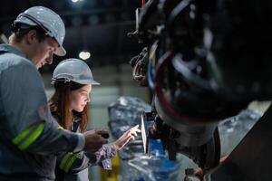 Factory engineer woman inspecting on machine with smart tablet. Worker works at machine robot arm. The welding machine with a remote system in an industrial factory. Artificial intelligence concept. photo