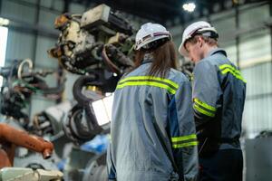 engineers check control heavy machine robot arm. Diverse Team of Industrial Robotics Engineers Gathered Around Machine. Professional Machinery Operators repair electric robot on bright digital panel. photo