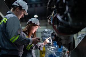 ingenieros cheque controlar pesado máquina robot brazo. diverso equipo de industrial robótica ingenieros reunido alrededor máquina. profesional maquinaria operadores reparar eléctrico robot en brillante digital panel. foto