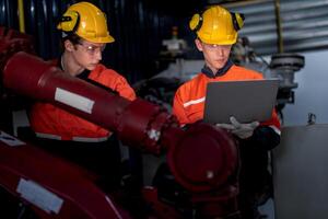 group of male engineer workers maintenance automatic robotic arm machine in a dark room factory. worker checking and repairing automatic robot hand machine. Worker wearing safety glasses and helmet. photo