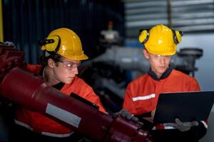 group of male engineer workers maintenance automatic robotic arm machine in a dark room factory. worker checking and repairing automatic robot hand machine. Worker wearing safety glasses and helmet. photo