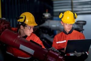 grupo de masculino ingeniero trabajadores mantenimiento automático robótico brazo máquina en un oscuro habitación fábrica. trabajador comprobación y reparando automático robot mano máquina. trabajador vistiendo la seguridad lentes y casco. foto