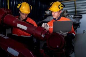 group of male engineer workers maintenance automatic robotic arm machine in a dark room factory. worker checking and repairing automatic robot hand machine. Worker wearing safety glasses and helmet. photo