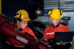 group of male engineer workers maintenance automatic robotic arm machine in a dark room factory. worker checking and repairing automatic robot hand machine. Worker wearing safety glasses and helmet. photo