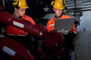 group of male engineer workers maintenance automatic robotic arm machine in a dark room factory. worker checking and repairing automatic robot hand machine. Worker wearing safety glasses and helmet. photo