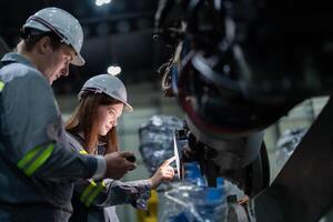 ingenieros cheque controlar pesado máquina robot brazo. diverso equipo de industrial robótica ingenieros reunido alrededor máquina. profesional maquinaria operadores reparar eléctrico robot en brillante digital panel. foto