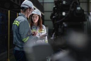 engineers check control heavy machine robot arm. Diverse Team of Industrial Robotics Engineers Gathered Around Machine. Professional Machinery Operators repair electric robot on bright digital panel. photo