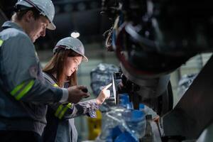 ingenieros cheque controlar pesado máquina robot brazo. diverso equipo de industrial robótica ingenieros reunido alrededor máquina. profesional maquinaria operadores reparar eléctrico robot en brillante digital panel. foto