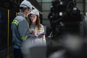 engineers check control heavy machine robot arm. Diverse Team of Industrial Robotics Engineers Gathered Around Machine. Professional Machinery Operators repair electric robot on bright digital panel. photo