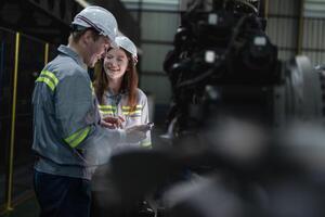 engineers check control heavy machine robot arm. Diverse Team of Industrial Robotics Engineers Gathered Around Machine. Professional Machinery Operators repair electric robot on bright digital panel. photo