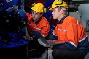 Business engineers meet and check control heavy machine robot arm. Diverse Team of Industrial Robotics Engineers Gathered Around machine. Professional Machinery Operator Use Industrial Digital Tablet. photo