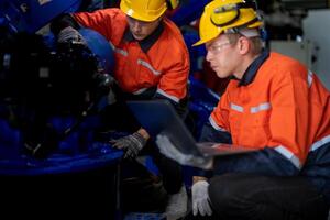Business engineers meet and check control heavy machine robot arm. Diverse Team of Industrial Robotics Engineers Gathered Around machine. Professional Machinery Operator Use Industrial Digital Tablet. photo