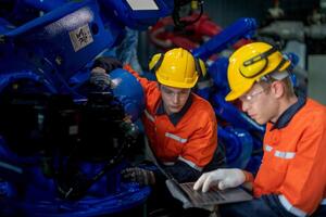 fábrica ingenieros inspeccionando en máquina con inteligente tableta. trabajador trabajos a pesado máquina robot brazo. el soldadura máquina con un remoto sistema en un industrial fábrica. artificial inteligencia concepto. foto