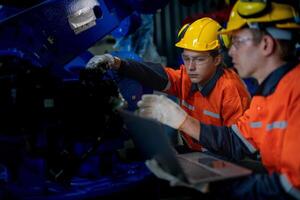 Business engineers meet and check control heavy machine robot arm. Diverse Team of Industrial Robotics Engineers Gathered Around machine. Professional Machinery Operator Use Industrial Digital Tablet. photo