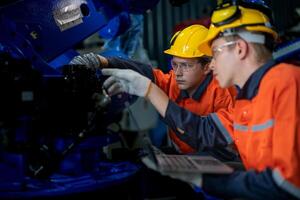 negocio ingenieros reunirse y cheque controlar pesado máquina robot brazo. diverso equipo de industrial robótica ingenieros reunido alrededor máquina. profesional maquinaria operador utilizar industrial digital tableta. foto