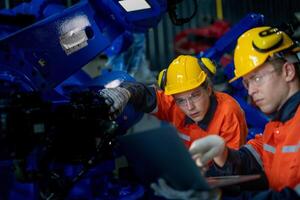 negocio ingenieros reunirse y cheque controlar pesado máquina robot brazo. diverso equipo de industrial robótica ingenieros reunido alrededor máquina. profesional maquinaria operador utilizar industrial digital tableta. foto