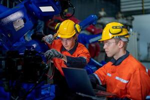 fábrica ingenieros inspeccionando en máquina con inteligente tableta. trabajador trabajos a pesado máquina robot brazo. el soldadura máquina con un remoto sistema en un industrial fábrica. artificial inteligencia concepto. foto