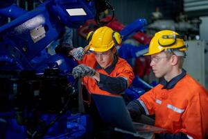 Business engineers meet and check control heavy machine robot arm. Diverse Team of Industrial Robotics Engineers Gathered Around machine. Professional Machinery Operator Use Industrial Digital Tablet. photo