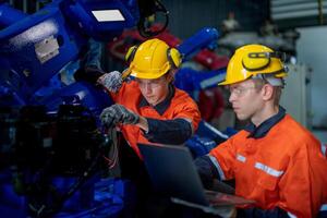 negocio ingenieros reunirse y cheque controlar pesado máquina robot brazo. diverso equipo de industrial robótica ingenieros reunido alrededor máquina. profesional maquinaria operador utilizar industrial digital tableta. foto