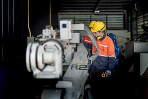 Engineer man checking the status of machine and used wrench to screw some part of equipment at CNC factory. Worker wearing safety glasses and helmet. Maintenance and repairing concept. photo
