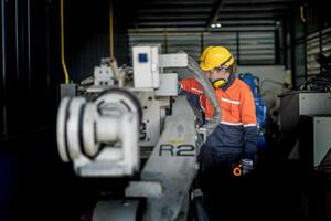 ingeniero hombre comprobación el estado de máquina y usado llave inglesa a tornillo algunos parte de equipo a cnc fábrica. trabajador vistiendo la seguridad lentes y casco. mantenimiento y reparando concepto. foto